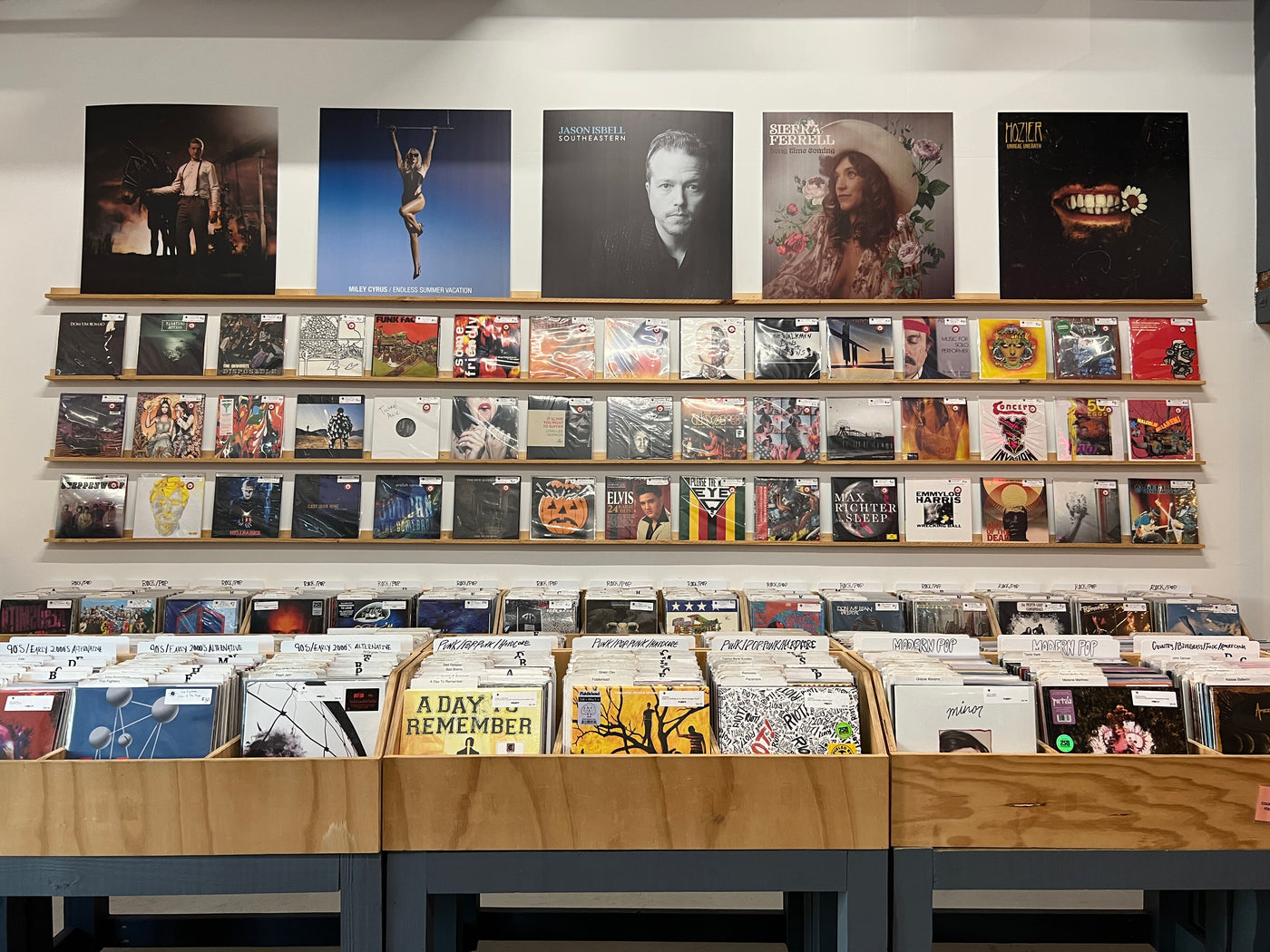 A wall of vinyl records, with bins of records below. 