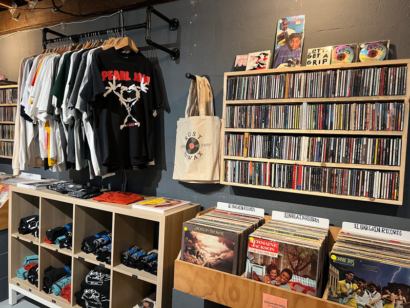 Back of the shop, featuring vintage t-shirts, Rust & Wax branded shirts & tote bags, $1 bargain records, and CD's.