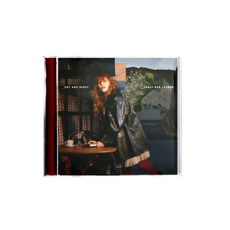 CD cover with image of Carly Rae Jepsen in a coat, standing at a table with a scenic background and text that reads 'Day And Night Carly Rae Jepsen'.