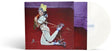 Ashnikko "Smoochies" album cover which is a colorful cover featuring a stylized illustration of Ashnikko on a red background, shown with a white vinyl record.