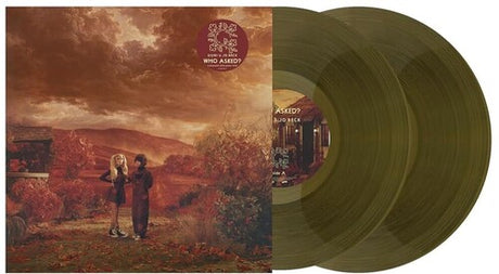 A vinyl record album shown with image of Domi & JD Beck against a orange hued nature backdrop and two translucent olive-green records partially visible behind it on a plain white background.