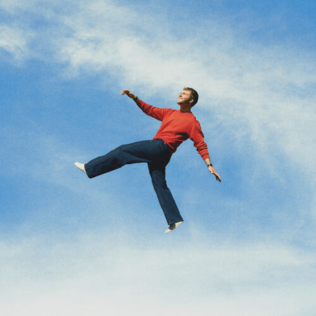 Alex Warren - Wildchild album cover, featuring Warren suspended in a cloudy blue sky