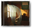 CD album cover for Beck's 'Ride Lonesome' with the title, featuring Beck sitting on a chair covered partially by sheer white curtains flowing from a window in a wood-paneled room.
