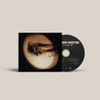 A CD album with its sleeve partially open, showing a black disc and cover art featuring a circular, abstract beige and brown image on a light warm gray background.