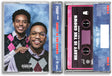 A cassette tape case shown with its front cover and pink cassette tape partially visible. The cover features Cordae and Anderson. Paak in argyle vests against a blue marbled backdrop, with a Parental Advisory label at the bottom. Text on the spine of the cassette case and on the pink cassette reads 'Heavy Is The Crown'
