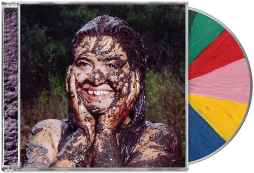 Compact disc jewel case showing Remi Wolf covered in mud and smiling with nature backdrop and a beach ball looking CD sticking out of the side of the case.