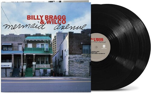 Album cover showing line of 2-story brick homes along a street with 'Billy Bragg & Wilco' written in the sky in red text and "mermaid avenue' black text underneath, with two Black vinyl records sticking out of the sleeve.