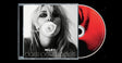 CD case featuring a black-and-white portrait of Miley holding a white rose in her lips, while the CD itself mix of red and black coloring and sticking out the side of the CD case.