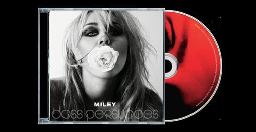 CD case featuring a black-and-white portrait of Miley holding a white rose in her lips, while the CD itself mix of red and black coloring and sticking out the side of the CD case.