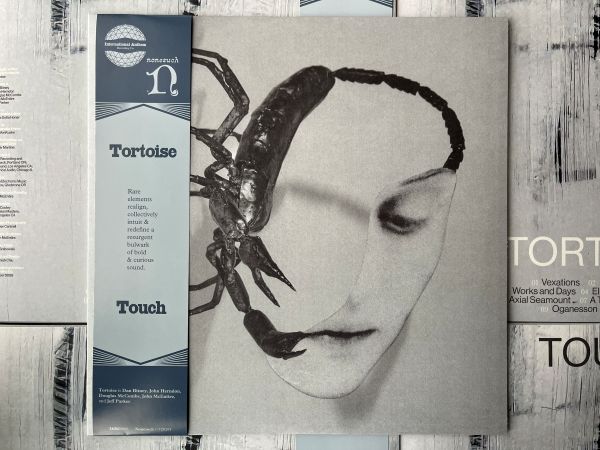 Tortoise "Touch" album cover featuring a face with a scorpion on it, with an OBI strip on the left side