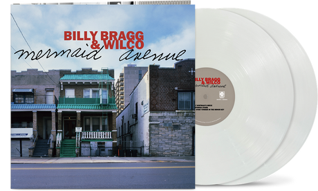 Album cover showing line of 2-story brick homes along a street with 'Billy Bragg & Wilco' written in the sky in red text and "mermaid avenue' black text underneath, with two white vinyl records sticking out of the sleeve.
