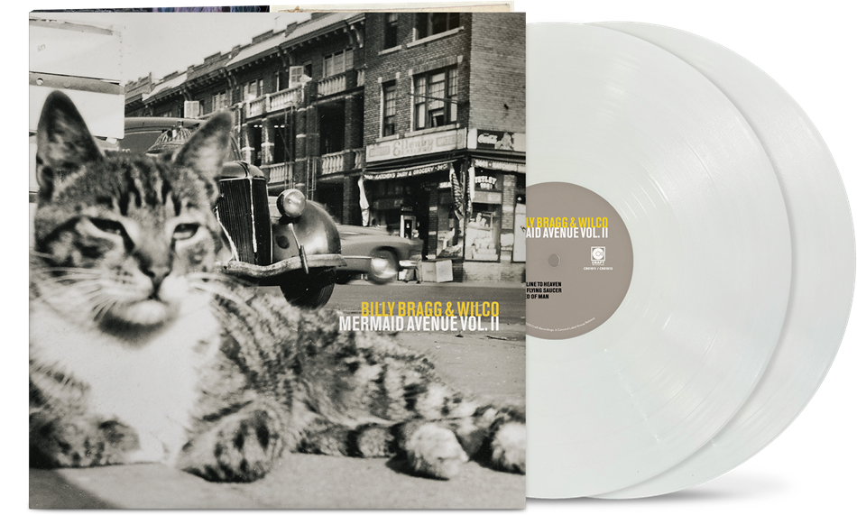 vinyl album cover showing a black and white image of a cat in front of a cityscape and car, with yellow text "Billy Bragg & Wilco' and white text "Mermaid Avenue Vol. II" and two white vinyl records sticking out of the side of the sleeve