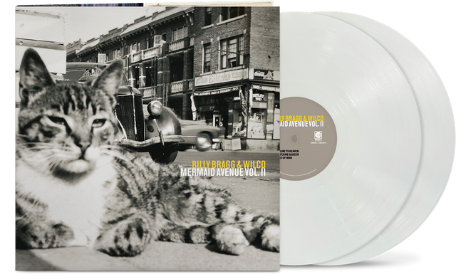 vinyl album cover showing a black and white image of a cat in front of a cityscape and car, with yellow text "Billy Bragg & Wilco' and white text "Mermaid Avenue Vol. II" and two white vinyl records sticking out of the side of the sleeve