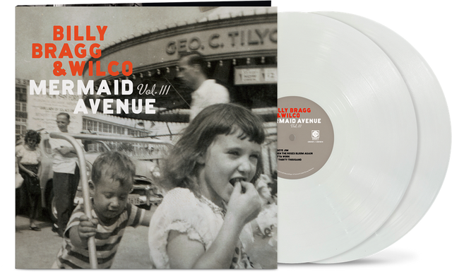 Vinyl album cover showing a child pushing another child on a hand cart in front of 3 other people and a large building (all in black & white) with orange text "Billy Bragg & Wilco" and white text "mermaid avenue vol. iii" with two white vinyl records sticking out the side of the sleeve.
