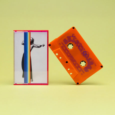 A retro-style cassette tape and its matching clear plastic case on a pale yellow background. The cassette is bright orange with purple text, and the case features a white cover with a black-and-white photo of a woman and a vertical rainbow stripe.
