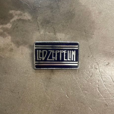 Vintage Led Zeppelin Enamel Pin silver text against black backdrop with silver stripes